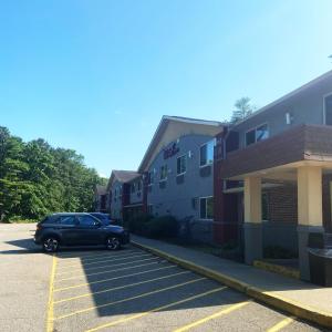 クイーンズベリーにあるRed Roof Inn Queensburyの建物の隣の駐車場に駐車された車