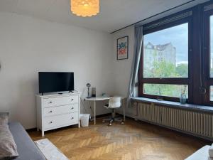 1 dormitorio con TV, escritorio y ventana en Stylish Apartment in the Heart of Hamburg, en Hamburgo