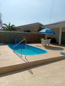 - Piscina con mesa y sombrilla en Casa em Guaratuba com piscina, en Guaratuba