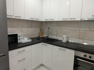 a kitchen with white cabinets and a sink and a microwave at Apartman Lukić Bratunac in Bratunac