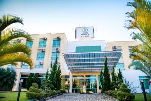 Un edificio con palmeras delante. en Hotel Aliança Express, en Rio do Sul