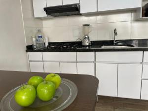 três maçãs verdes em um prato de vidro sobre uma mesa na cozinha em Confortable Hospedaje- Ubicación Estratégica Bogotá em Bogotá
