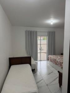 Una habitación blanca con dos camas y una ventana. en Casa em Guaratuba com piscina, en Guaratuba 23 fotos más