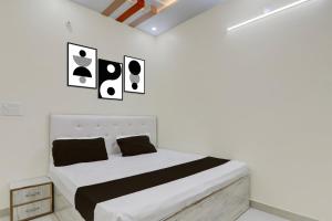 a white bedroom with a bed with three pictures on the wall at SPOT ON Kanhaiya Hotel in Lucknow