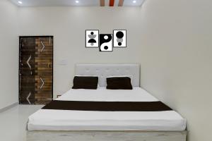 a bedroom with a white bed with black pillows at SPOT ON Kanhaiya Hotel in Lucknow