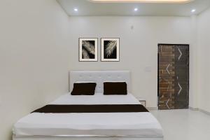 a white bedroom with a white bed with black pillows at SPOT ON Kanhaiya Hotel in Lucknow