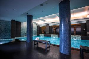 a pool in a hotel with columns and a tub at Quay West Suites Melbourne in Melbourne