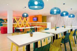 a restaurant with white tables and chairs and blue lights at ibis Styles Duesseldorf-Neuss in Neuss