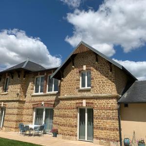 a brick house with a table and chairs in front of it at Gîte du Château avec Piscine Intérieure in Ligny-le-Châtel