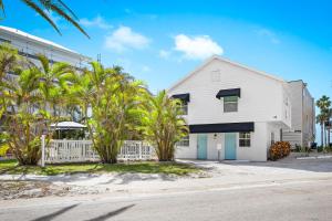 a white house with palm trees in front of a building at Parrot Beach Cottages Suite #1 in Bailey Hall