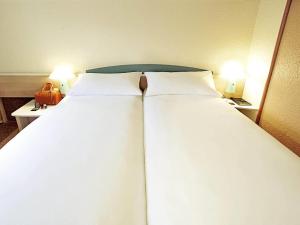 two large beds in a hotel room with two lamps at ibis Chambery in Chambéry
