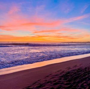 a sunset at the beach with footprints in the sand at Your Place in Estoril in Estoril