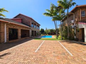 a brick driveway in front of a building with a pool at DuneSide Guesthouse in Richards Bay