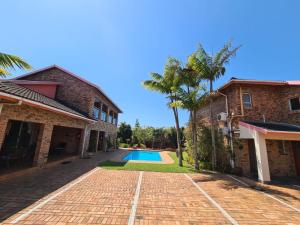 a house with a brick driveway and a swimming pool at DuneSide Guesthouse in Richards Bay +8 photos