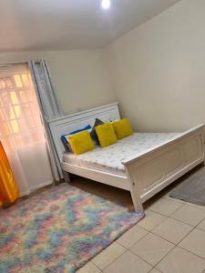 un letto bianco con cuscini gialli in una stanza di Blissful haven Stays a Ruaka
