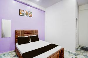 a bedroom with a bed in a room with purple walls at Hotel O MN Palace in Jabalpur