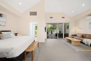 ein Schlafzimmer mit einem großen Bett und einer Couch in der Unterkunft Beachside Bungalow on Shelly Beach in Caloundra