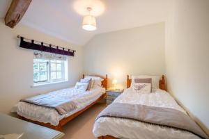 a bedroom with two beds and a window at Watts Cottage in Upton