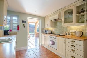 a kitchen with white cabinets and a tile floor at Watts Cottage in Upton +17 photos