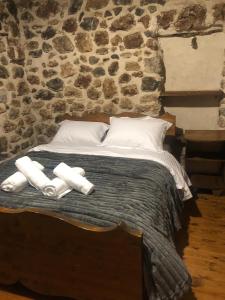 a bed with white pillows and a stone wall at Andromahi Stone House in Stemnitsa +1 photo
