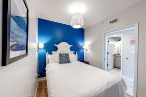 a bedroom with a white bed with a blue wall at Silver Beach 704 in Romar Beach