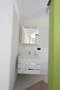 a white bathroom with a sink and a mirror at Winter'sches Haus in Nördlingen