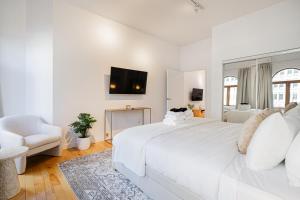 ein weißes Schlafzimmer mit einem großen weißen Bett und einem Stuhl in der Unterkunft La Galerie Privée Luxe & Impeccable Stay in Montreal