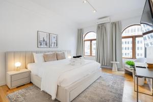 ein weißes Schlafzimmer mit einem großen weißen Bett und einem Schreibtisch in der Unterkunft La Galerie Privée Luxe & Impeccable Stay in Montreal