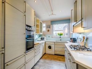 eine Küche mit weißen Schränken und einer Waschmaschine und einem Trockner in der Unterkunft 3 Bed in Oban 86398 in Oban