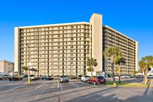 パナマ・シティ・ビーチにあるThe Commodore #302Bの駐車場に車が駐車されている大きな建物