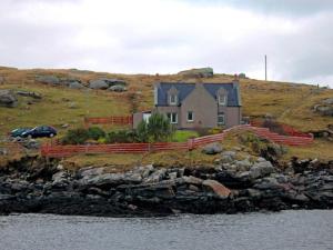 a house on top of a hill next to the water at 3 Bed in Isle of Barra CA295 in Ersary