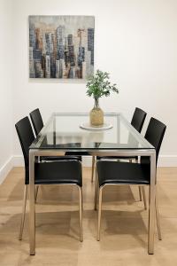 伦敦2 bed flat, sleeps 8, driveway, 5 Mins to Brixton的玻璃餐桌，黑色椅子，花瓶里插着一盆植物 更多4张照片