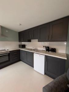 a kitchen with black cabinets and white appliances at Corporate Nest Sallins in Balnacart