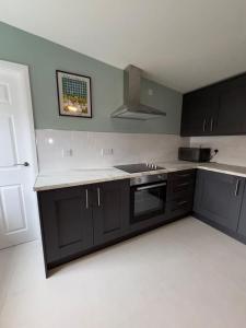 a kitchen with black cabinets and a white counter top at Corporate Nest Sallins in Balnacart +3 photos