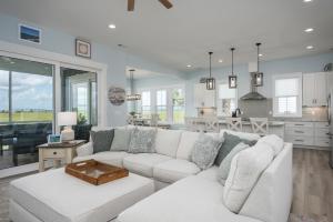 a living room with a white couch and a kitchen at New Custom Built 5-Bedroom Coastal Retreat - Harbor Island, SC in Cedar Reef Villas