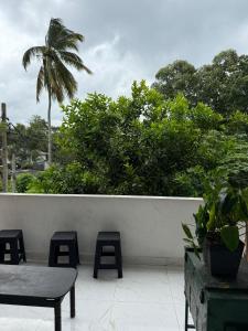 a patio with a table and stools and a palm tree at Kandy Home stay - Haloluwa in Katugastota