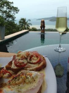 a plate of food on a table with a glass of wine at Villa Taling Ngam Amazing Sea view in Taling Ngam Beach