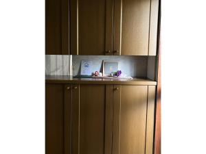 a kitchen with brown cabinets and a clock on a counter at Guest House Aoi - Vacation STAY 20032 in Mitsugarasuchō