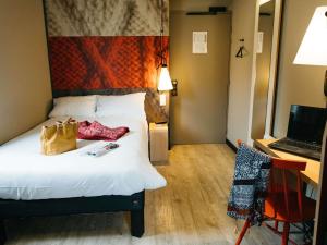 a hotel room with a bed and a desk and a laptop at ibis Quimper in Quimper +68 photos