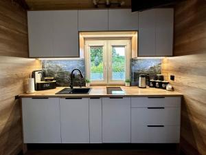 a kitchen with white cabinets and a sink and a window at Chatka u Mańka in Świeradów-Zdrój