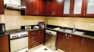 eine Küche mit Holzschränken, einem Herd und einer Spüle in der Unterkunft Shams Wa Bahar Vacation Homes Rental in Dubai