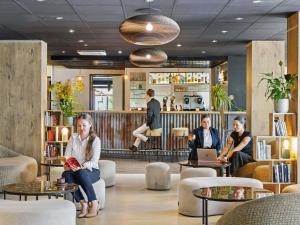 eine Gruppe von Menschen, die in einer Lobby sitzen in der Unterkunft ibis Paris Porte D'Orleans in Montrouge