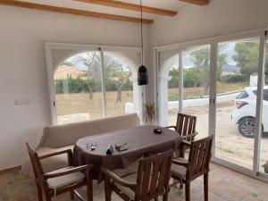 a dining room with a table and chairs and windows at Villa con encanto en Benimarco in Paratella