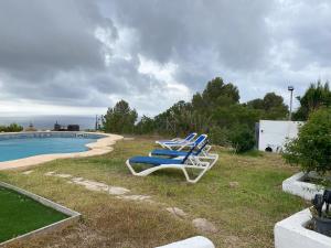 a group of lawn chairs sitting next to a pool at Villa con encanto en Benimarco in Paratella