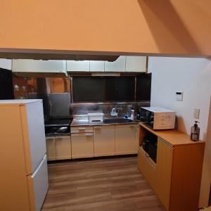 La cuisine est équipée de placards bruns et d'un réfrigérateur blanc. dans l'établissement Atagawa Hutte - Vacation STAY 19932, à Okawa