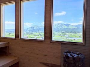 a room with three windows with mountains in the background at Minamiaso Sauna 5GAKU - Vacation STAY 24181v in Minami Aso +7 photos