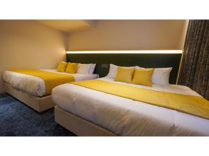two beds in a hotel room with yellow pillows at THE GALA HOTEL UMEDA - Vacation STAY 24228v in Osaka