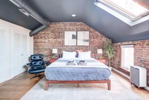 ein Schlafzimmer mit einer Ziegelwand, einem Bett und einem Stuhl in der Unterkunft King Bed Free Parking Brick Carriage House in Alexandria + 69 Fotos