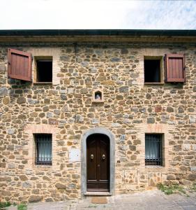 een stenen gebouw met een bruine deur en ramen bij Casa Burelli in Montalcino