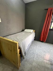 a bed in a room with a red curtain at Jacaranda Alojamiento in Ezeiza +1 photo